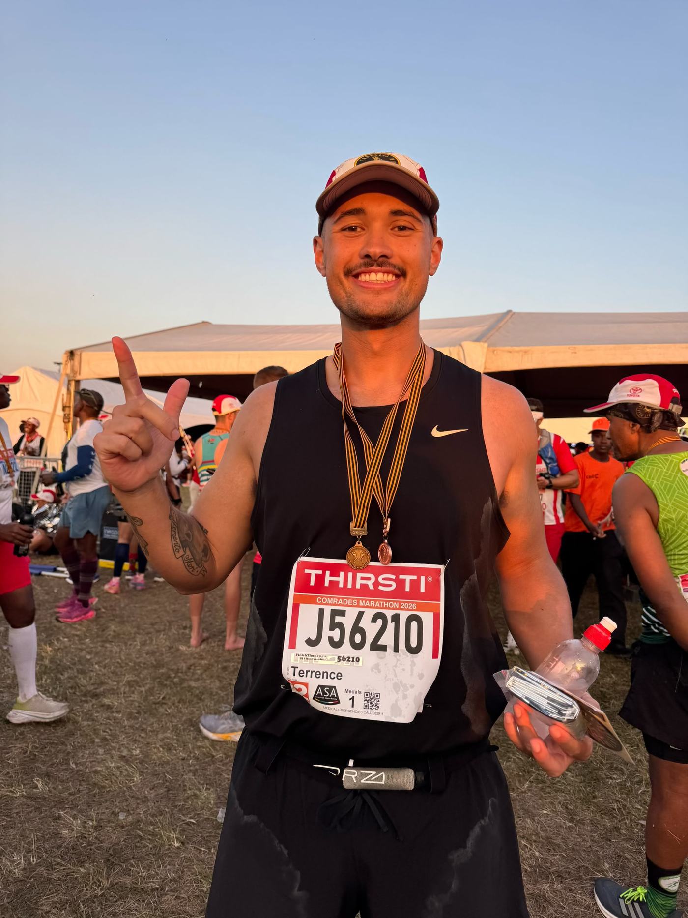 Terrence at the Comrades Marathon 2026 finish, wearing a medal and holding a second finisher medal.